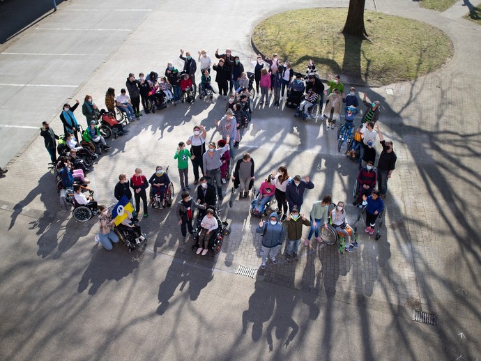 Schülerinnen und Schüler stellen Peace-Zeichen auf dem Schulhof nach